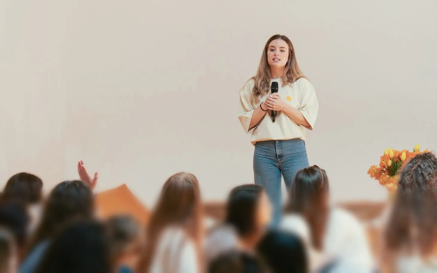 Carmen Piqueras, micrófono en mano, hablando ante un grupo de mujeres sentadas en el suelo